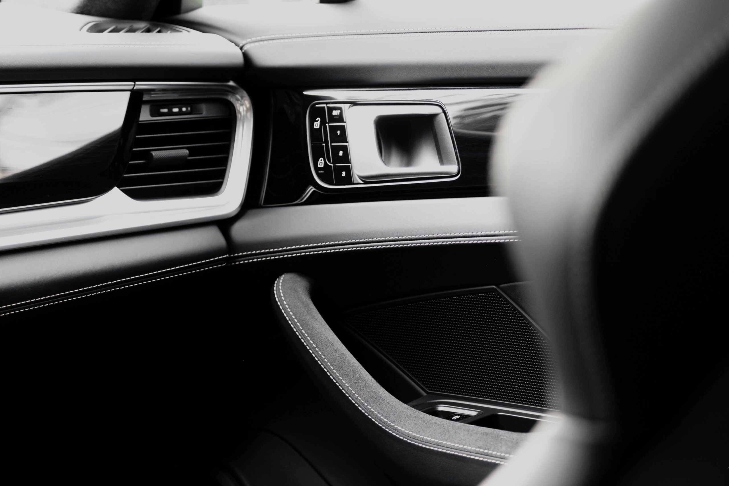 Close-up of a luxury car interior with a focus on the sleek dashboard and leather stitching.